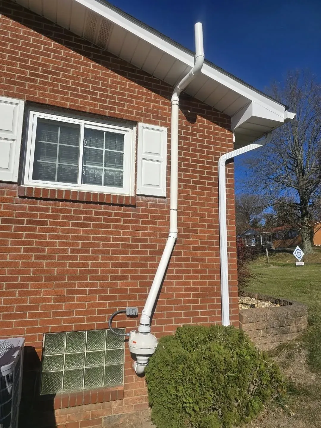 Radon mitigation fan and vent pipe installed on a brick home in York County